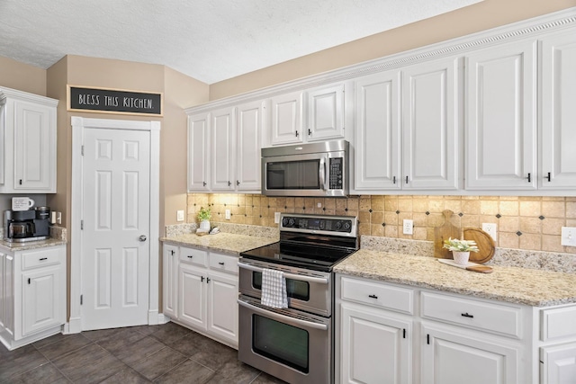 842 Shun Pike, Cottontown, TN 37048 - kitchen with appliances with stainless steel finishes, white cabinetry, decorative backsplash, light stone counters, and dark tile patterned flooring