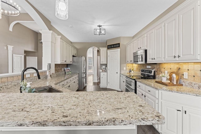 842 Shun Pike, Cottontown, TN 37048 - kitchen featuring stainless steel appliances, a sink, arched walkways, light stone counters, and backsplash