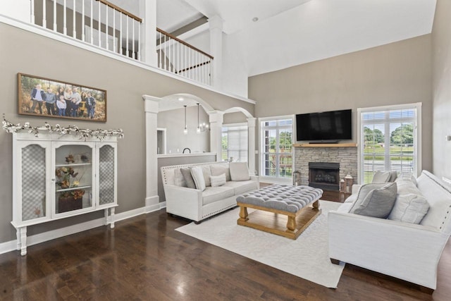 842 Shun Pike, Cottontown, TN 37048 - living room featuring a towering ceiling, wood finished floors, a stone fireplace, ornate columns, and baseboards