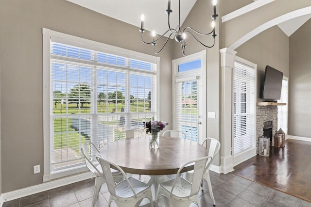 842 Shun Pike, Cottontown, TN 37048 - tiled dining space with baseboards, high vaulted ceiling, a stone fireplace, arched walkways, and decorative columns