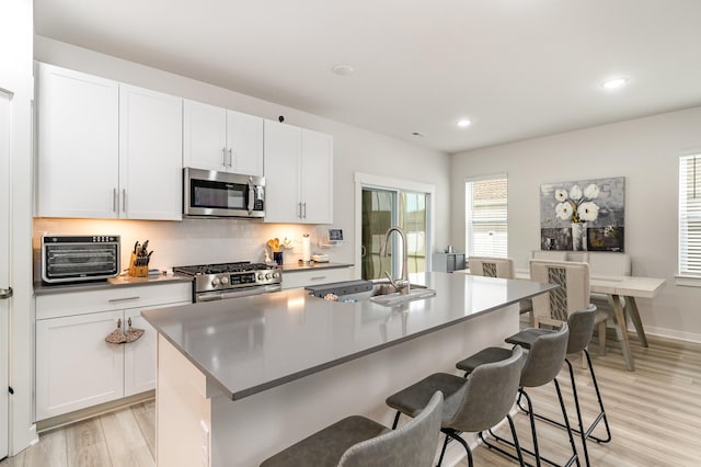 120 Ravens Crest Ave, Mount Juliet, TN 37122 - kitchen featuring appliances with stainless steel finishes, a sink, a breakfast bar, tasteful backsplash, and light wood-style floors