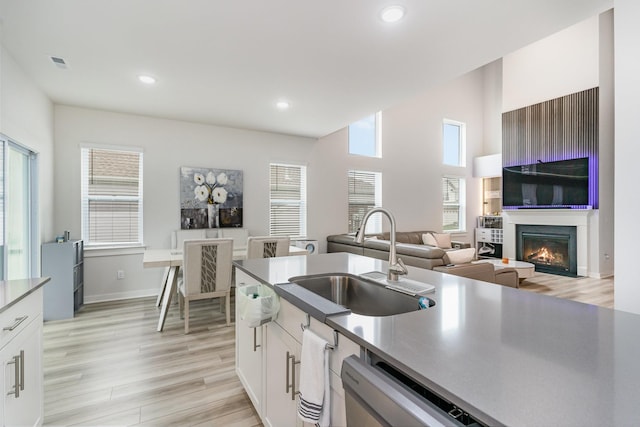 120 Ravens Crest Ave, Mount Juliet, TN 37122 - kitchen with a sink, dishwasher, light wood-type flooring, white cabinetry, and a glass covered fireplace