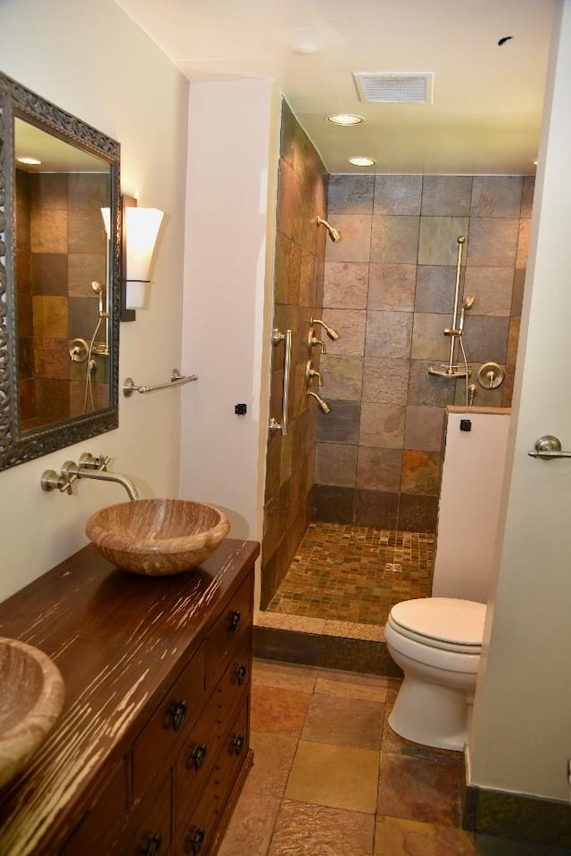 1314 Burton Valley Rd, Nashville, TN 37215 - bathroom featuring toilet, tiled shower, double vanity, and stone finish floors