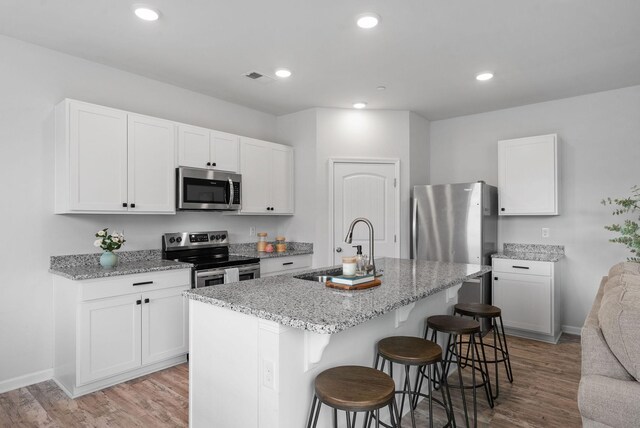 148 Victory Cir, Ashland City, TN 37015 - kitchen with stainless steel appliances, a sink, a breakfast bar, light stone countertops, and recessed lighting