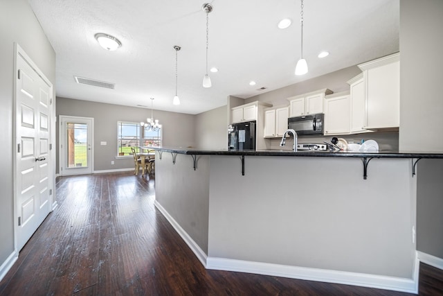 1426 Alamo Ave, Murfreesboro, TN 37129 - kitchen featuring black appliances, a chandelier, baseboards, a breakfast bar area, and dark countertops