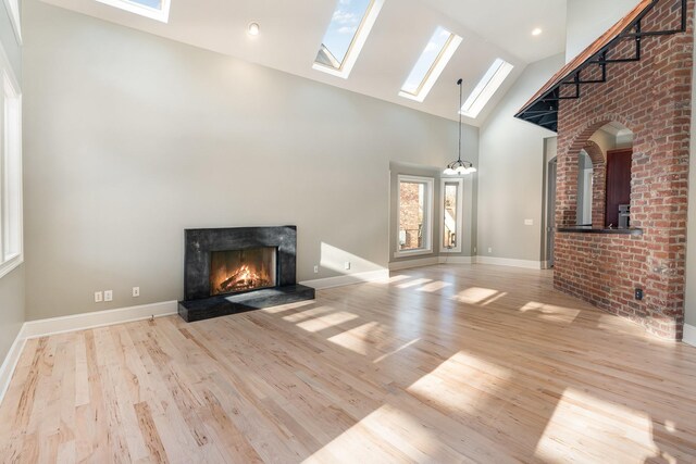 1107 Stonebridge Park Dr, Franklin, TN 37069 - unfurnished living room with a skylight, high vaulted ceiling, a fireplace, wood finished floors, and baseboards