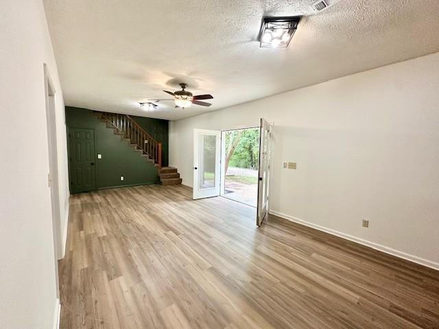 807 Poplar Dr, Centerville, TN 37033 - unfurnished living room with stairs, wood finished floors, baseboards, ceiling fan, and a textured ceiling