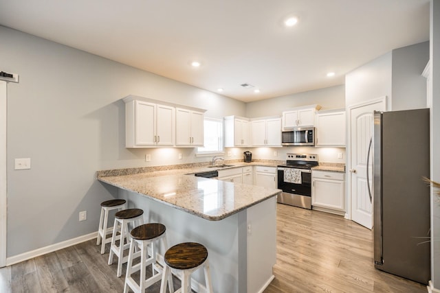 1110 Colonel Reuben Searcy Ct, Murfreesboro, TN 37129 - kitchen featuring appliances with stainless steel finishes, a peninsula, light wood-type flooring, white cabinets, and light stone counters