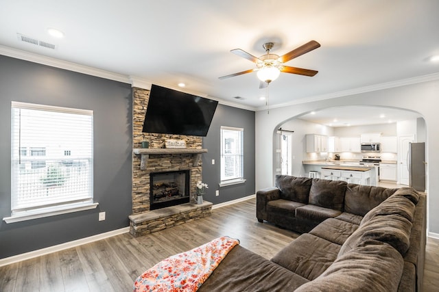1110 Colonel Reuben Searcy Ct, Murfreesboro, TN 37129 - living room featuring arched walkways, a ceiling fan, light wood-style floors, a stone fireplace, and baseboards