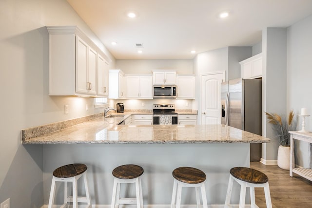 1110 Colonel Reuben Searcy Ct, Murfreesboro, TN 37129 - kitchen with appliances with stainless steel finishes, a peninsula, dark wood-style flooring, white cabinets, and recessed lighting