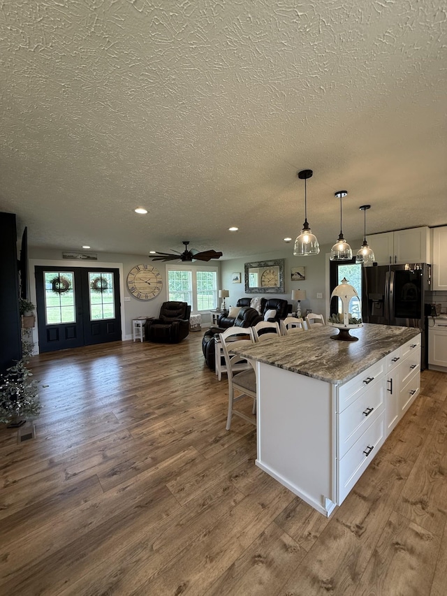 285 Shrum Ln, Lafayette, TN 37083 - kitchen featuring open floor plan, a textured ceiling, white cabinets, plenty of natural light, and wood finished floors