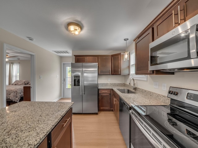 201 Quarry Overlook Way, Clarksville, TN 37043 - kitchen with appliances with stainless steel finishes, a sink, light wood-style flooring, light stone counters, and hanging light fixtures