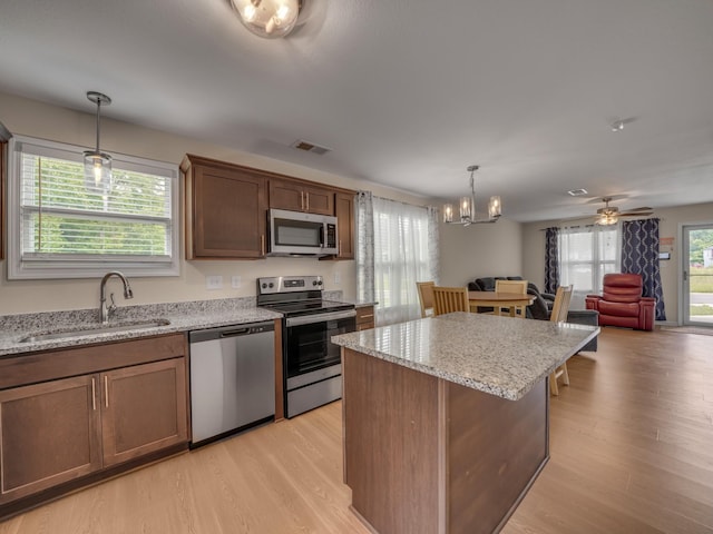 201 Quarry Overlook Way, Clarksville, TN 37043 - kitchen featuring stainless steel appliances, a sink, a center island, light wood finished floors, and light stone counters