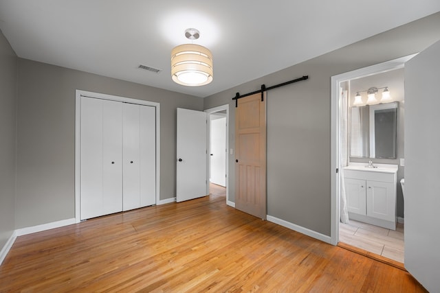 109 Hazelwood Dr, Hendersonville, TN 37075 - unfurnished bedroom featuring a barn door, light wood-type flooring, baseboards, a closet, and connected bathroom