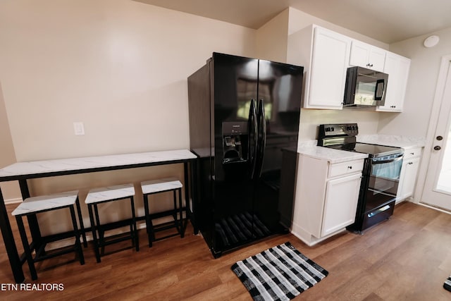 1799 Baker Hwy, Huntsville, TN 37756 - kitchen with black appliances, wood finished floors, white cabinetry, and light stone counters