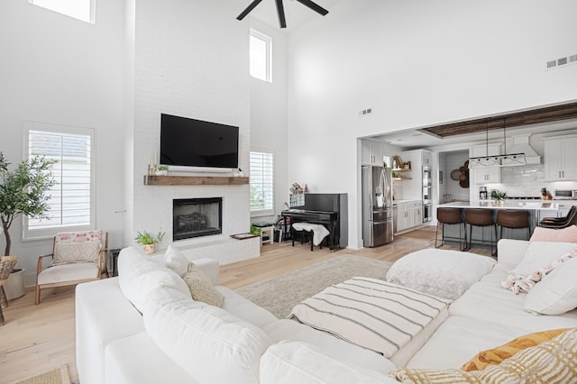 7546 Delancey Dr, College Grove, TN 37046 - living room featuring ceiling fan, a high ceiling, light wood finished floors, healthy amount of natural light, and a fireplace