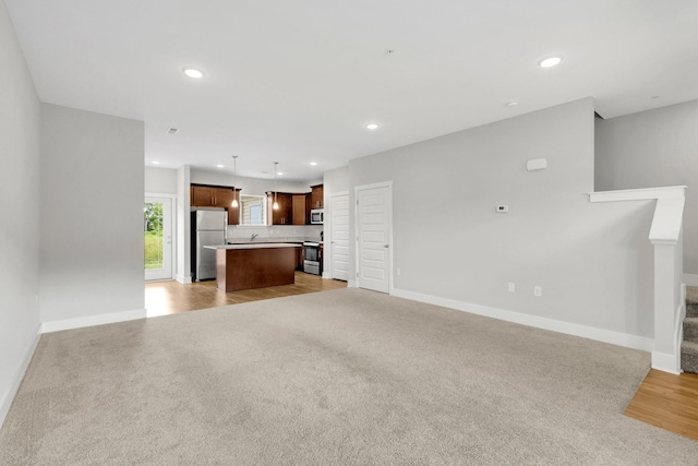 1081 Wells Way, Spring Hill, TN 37174 - unfurnished living room featuring stairway, baseboards, light colored carpet, recessed lighting, and light wood-type flooring