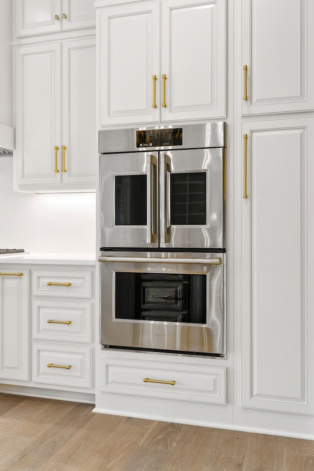 724 Bradshaw Rd, Lebanon, TN 37087 - kitchen with double oven, white cabinets, and wood finished floors
