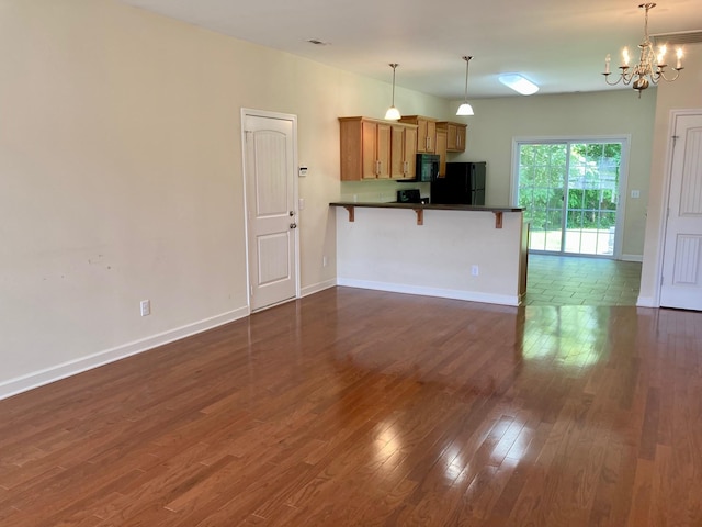 507 Whirlaway Ct, Burns, TN 37029 - kitchen featuring black appliances, a peninsula, a breakfast bar area, dark countertops, and dark wood-type flooring