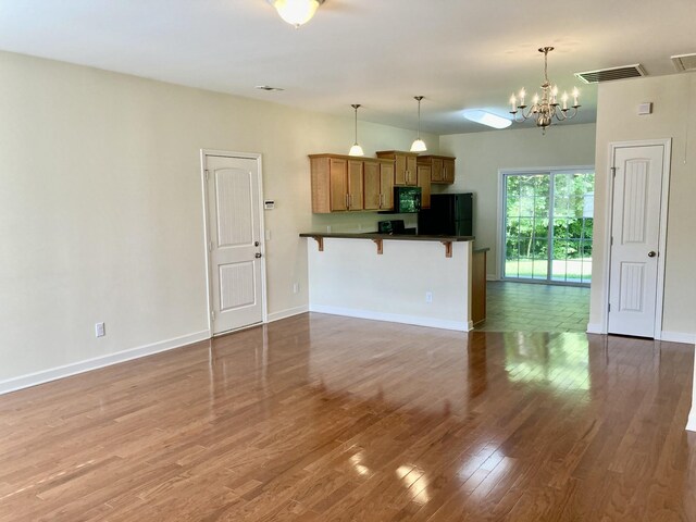 507 Whirlaway Ct, Burns, TN 37029 - kitchen featuring black appliances, brown cabinets, a breakfast bar area, dark countertops, and wood finished floors
