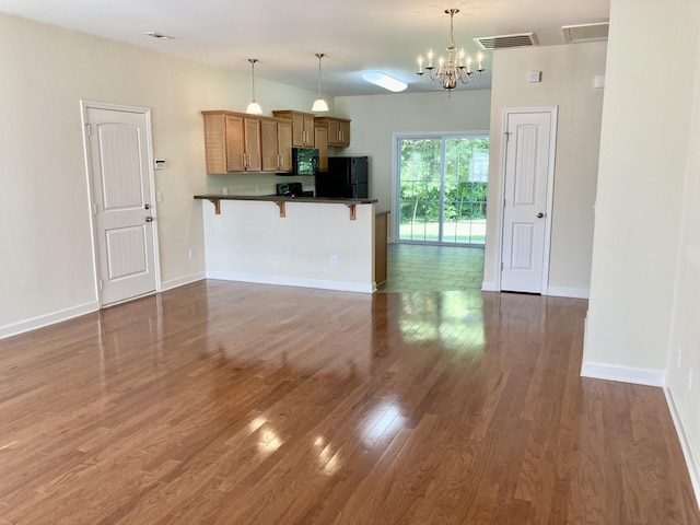 507 Whirlaway Ct, Burns, TN 37029 - kitchen with black appliances, dark countertops, a breakfast bar area, wood finished floors, and a chandelier