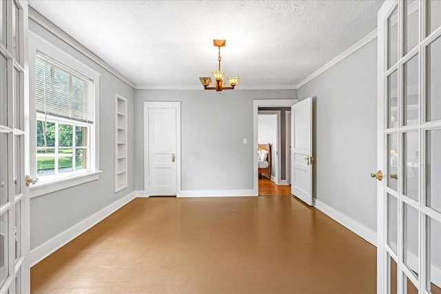 256 Tanksley Ave, Nashville, TN 37211 - unfurnished room with built in shelves, crown molding, a chandelier, baseboards, and a textured ceiling