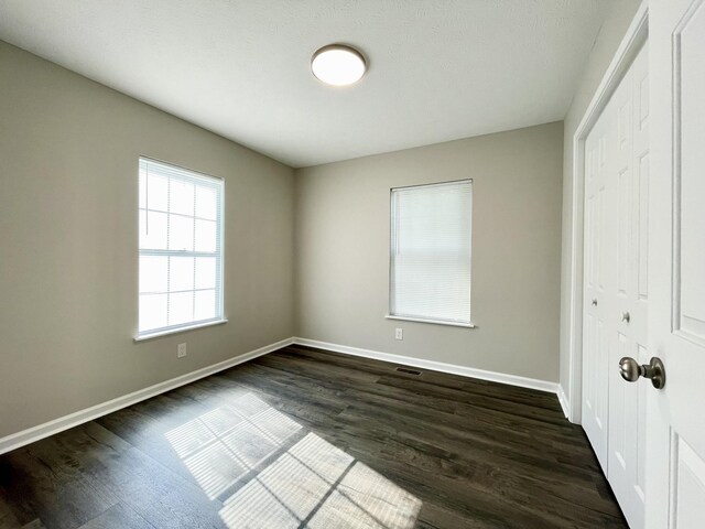 1004 E Railroad St, Waverly, TN 37185 - unfurnished bedroom with baseboards, dark wood finished floors, and a closet
