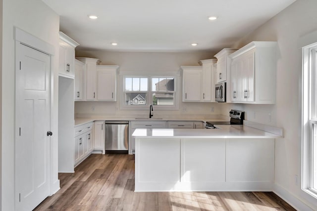 1038 Camden Trl, Greenbrier, TN 37073 - kitchen featuring stainless steel appliances, a peninsula, light countertops, a sink, and light wood finished floors