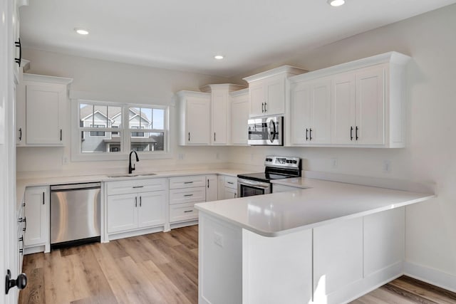 1038 Camden Trl, Greenbrier, TN 37073 - kitchen featuring stainless steel appliances, a sink, white cabinetry, light wood-type flooring, and a peninsula