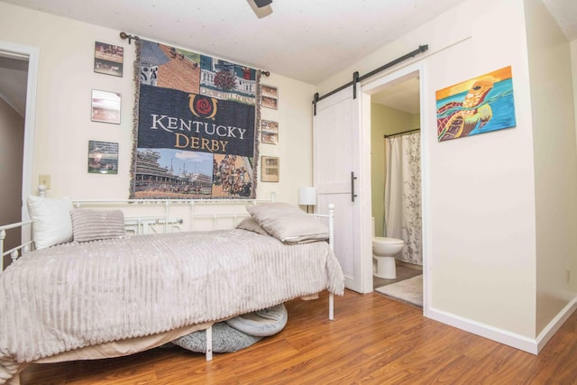 813 Stiner Ln, La Follette, TN 37766 - bedroom featuring wood finished floors, a barn door, ensuite bathroom, and baseboards