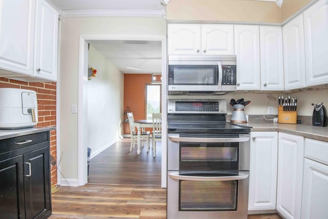 813 Stiner Ln, La Follette, TN 37766 - kitchen with stainless steel appliances, white cabinetry, crown molding, and light wood-style flooring