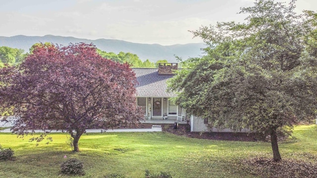 813 Stiner Ln, La Follette, TN 37766 - obstructed view of property featuring a front lawn, a mountain view, covered porch, and a shingled roof