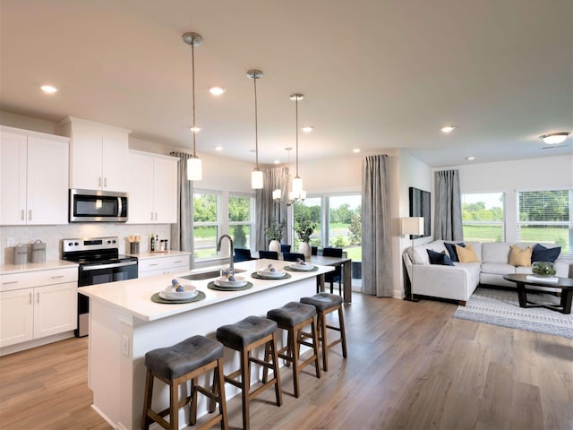 1343 Beasley Blvd, Mount Juliet, TN 37122 - kitchen with appliances with stainless steel finishes, a sink, a breakfast bar area, a kitchen island with sink, and white cabinetry