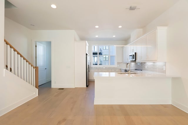 621 Live Life Ln, Nashville, TN 37207 - kitchen featuring stainless steel appliances, a sink, light countertops, white cabinets, and a peninsula