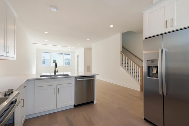 621 Live Life Ln, Nashville, TN 37207 - kitchen with stainless steel appliances, a sink, a peninsula, white cabinets, and light wood-type flooring