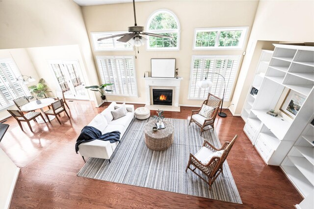 8825 Caswick Ct, Nolensville, TN 37135 - living room featuring wood finished floors, a towering ceiling, a glass covered fireplace, a ceiling fan, and healthy amount of natural light