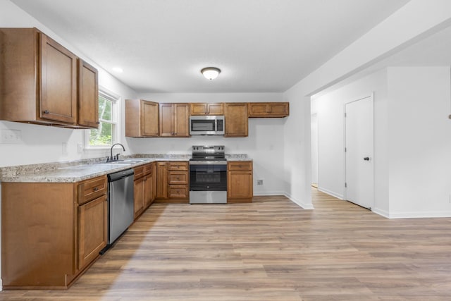 382 Louise Ln, Clarksville, TN 37042 - kitchen with appliances with stainless steel finishes, a sink, brown cabinetry, light wood-type flooring, and light countertops