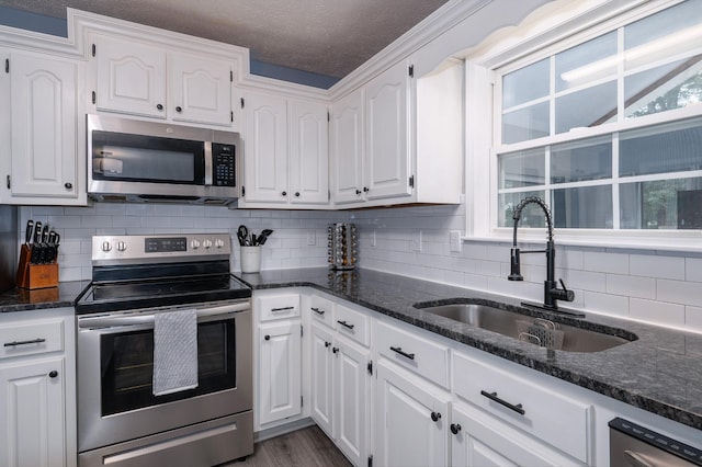 115 Pin Oaks Ln, Hohenwald, TN 38462 - kitchen featuring appliances with stainless steel finishes, a sink, white cabinetry, tasteful backsplash, and dark stone countertops