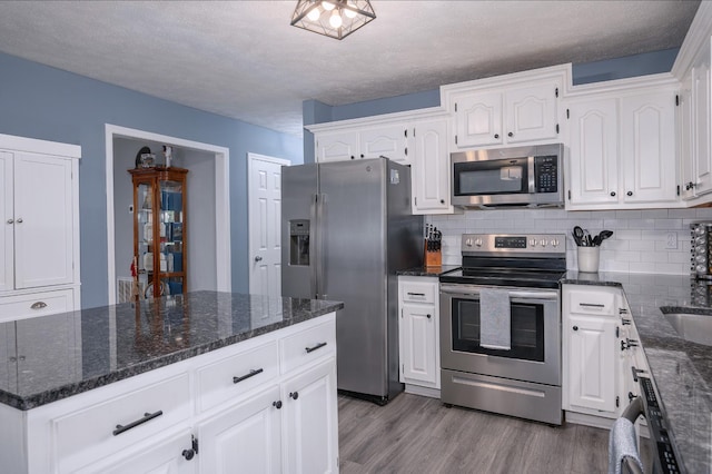 115 Pin Oaks Ln, Hohenwald, TN 38462 - kitchen with appliances with stainless steel finishes, wood finished floors, backsplash, white cabinets, and dark stone countertops