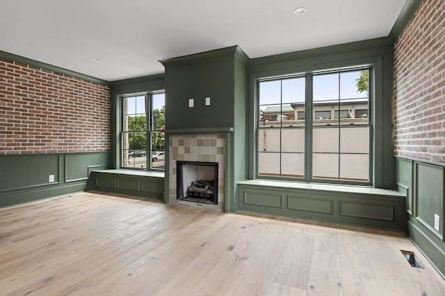 1701 Portland Ave Unit E, Nashville, TN 37212 - unfurnished living room featuring brick wall, a fireplace, a decorative wall, wood finished floors, and wainscoting