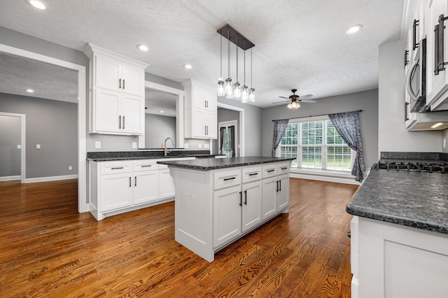 167 Lancaster St, Hillsboro, TN 37342 - kitchen with a textured ceiling, dark countertops, a center island, white cabinetry, and ceiling fan