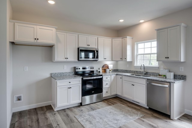 1502 Rock Springs Rd, Cumberland Furnace, TN 37051 - kitchen with appliances with stainless steel finishes, a sink, light stone countertops, light wood-style flooring, and white cabinetry