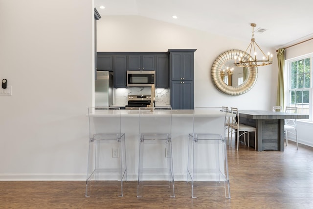 3164 Winberry Dr, Franklin, TN 37064 - kitchen with stainless steel appliances, a chandelier, a kitchen bar, dark wood finished floors, and hanging light fixtures
