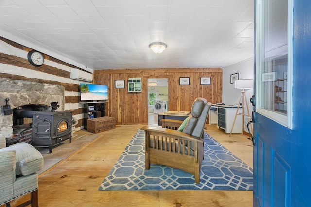 379 Gunson Ridge Rd, Cumberland City, TN 37050 - living area with a wood stove, hardwood / wood-style floors, separate washer and dryer, a wall mounted air conditioner, and wooden walls