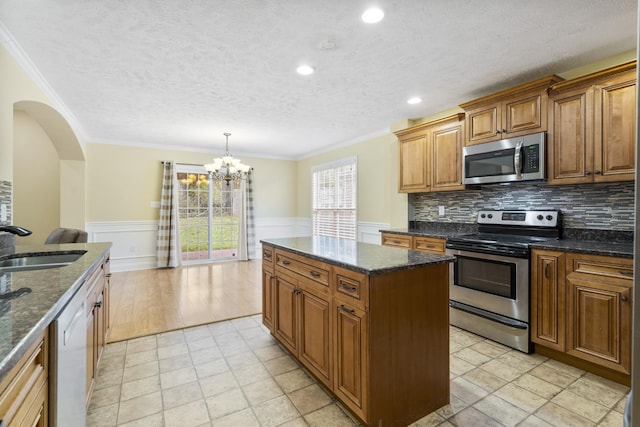 2240 Killington Dr, Clarksville, TN 37040 - kitchen with stainless steel appliances, a sink, brown cabinets, a center island, and ornamental molding