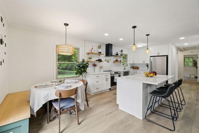 170 Old Carters Creek Pike, Franklin, TN 37064 - kitchen with appliances with stainless steel finishes, wall chimney exhaust hood, white cabinetry, light countertops, and light wood finished floors