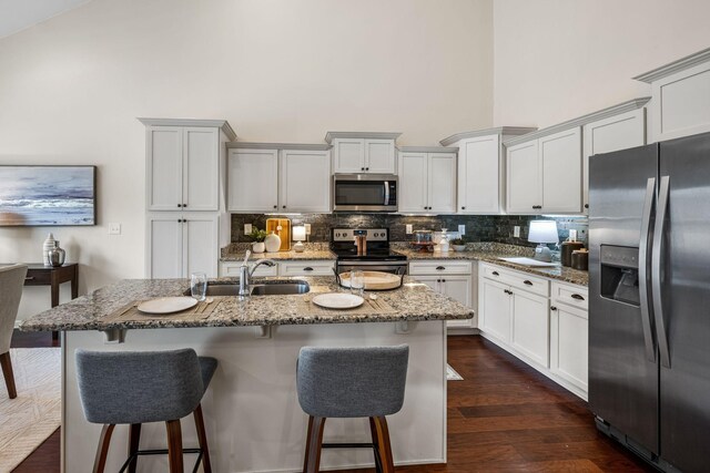 7504 Beechnut Way, Fairview, TN 37062 - kitchen featuring stainless steel appliances, a towering ceiling, decorative backsplash, light stone countertops, and a breakfast bar