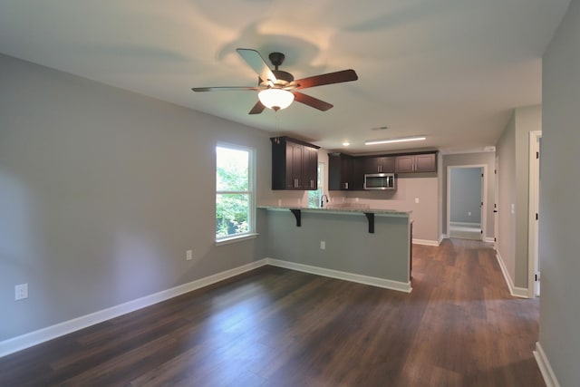 206 Sunset Dr, Red Boiling Springs, TN 37150 - kitchen with stainless steel microwave, a peninsula, a kitchen breakfast bar, a ceiling fan, and dark wood finished floors