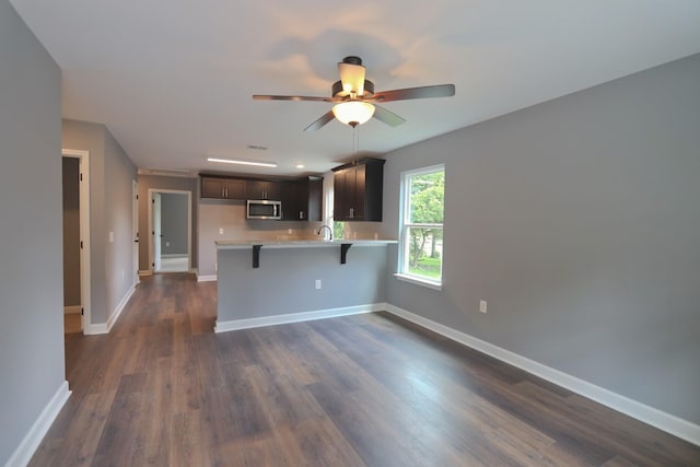 174 Dale St, Red Boiling Springs, TN 37150 - kitchen with stainless steel microwave, a peninsula, light countertops, a kitchen bar, and dark wood-type flooring