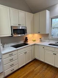 5544 S New Hope Rd, Hermitage, TN 37076 - kitchen featuring stainless steel microwave, black electric stovetop, light countertops, white cabinetry, and lofted ceiling
